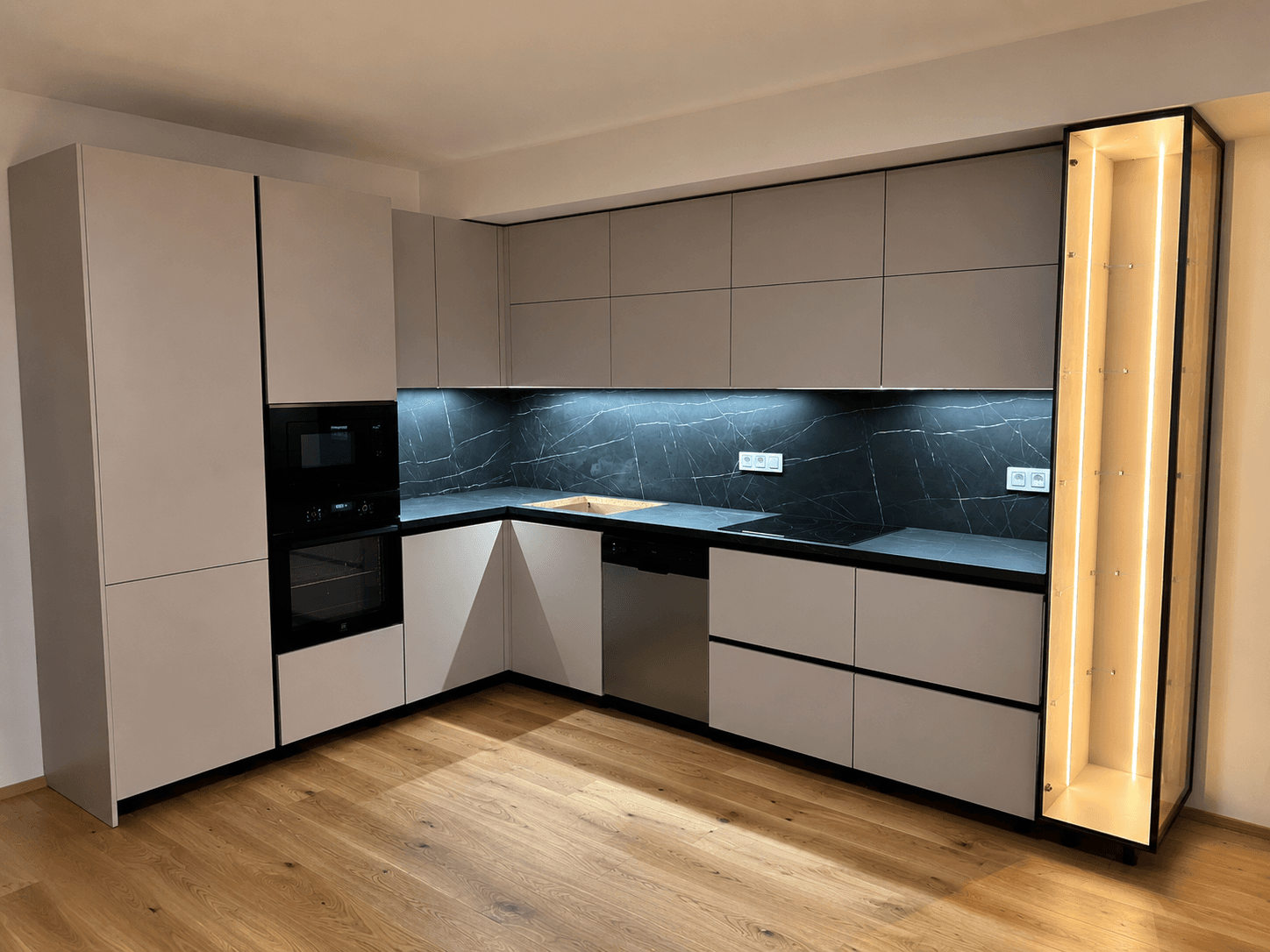Corner kitchen with grey marble splashback and lit display cabinet