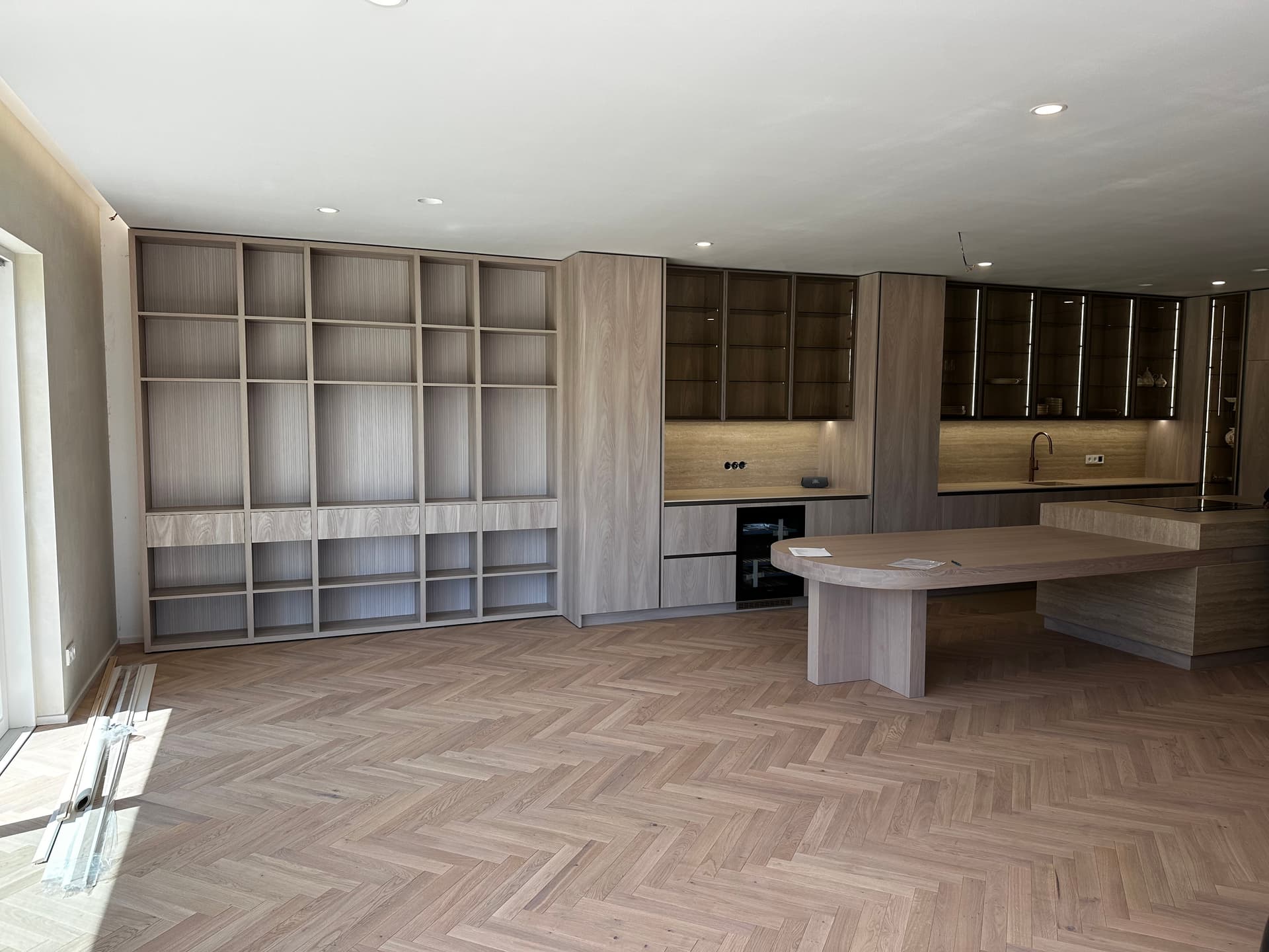 Wall-length custom casegoods with integrated kitchen and herringbone oak floor
